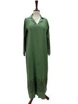 Green dress on a mannequin against a white paneled wall.